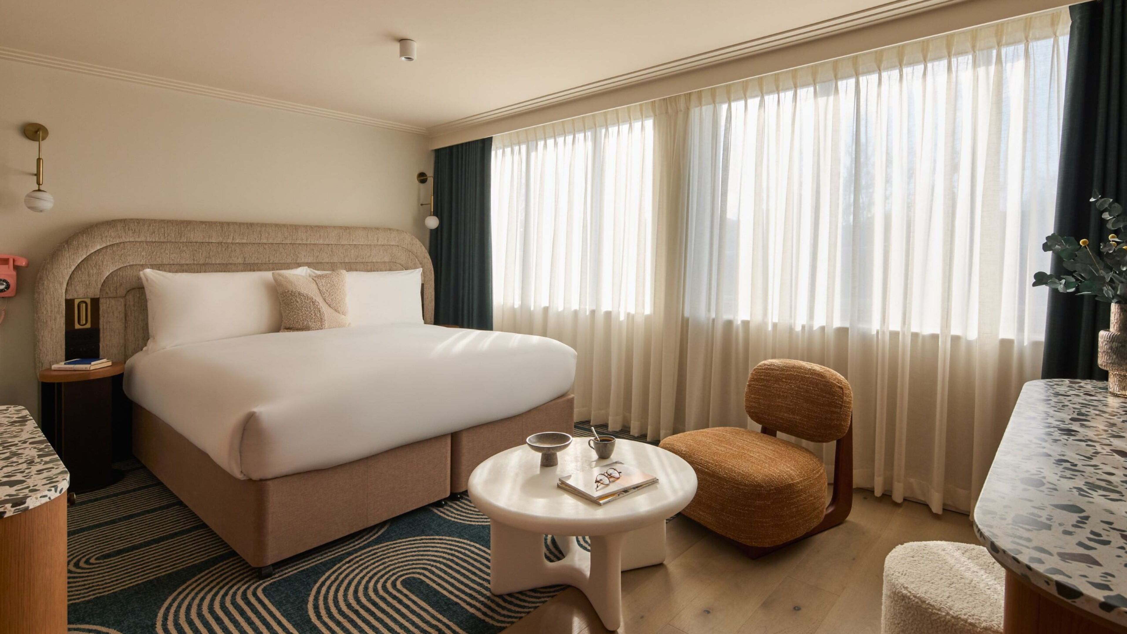 Guest room with modern chair, neutral tones, and soft natural light